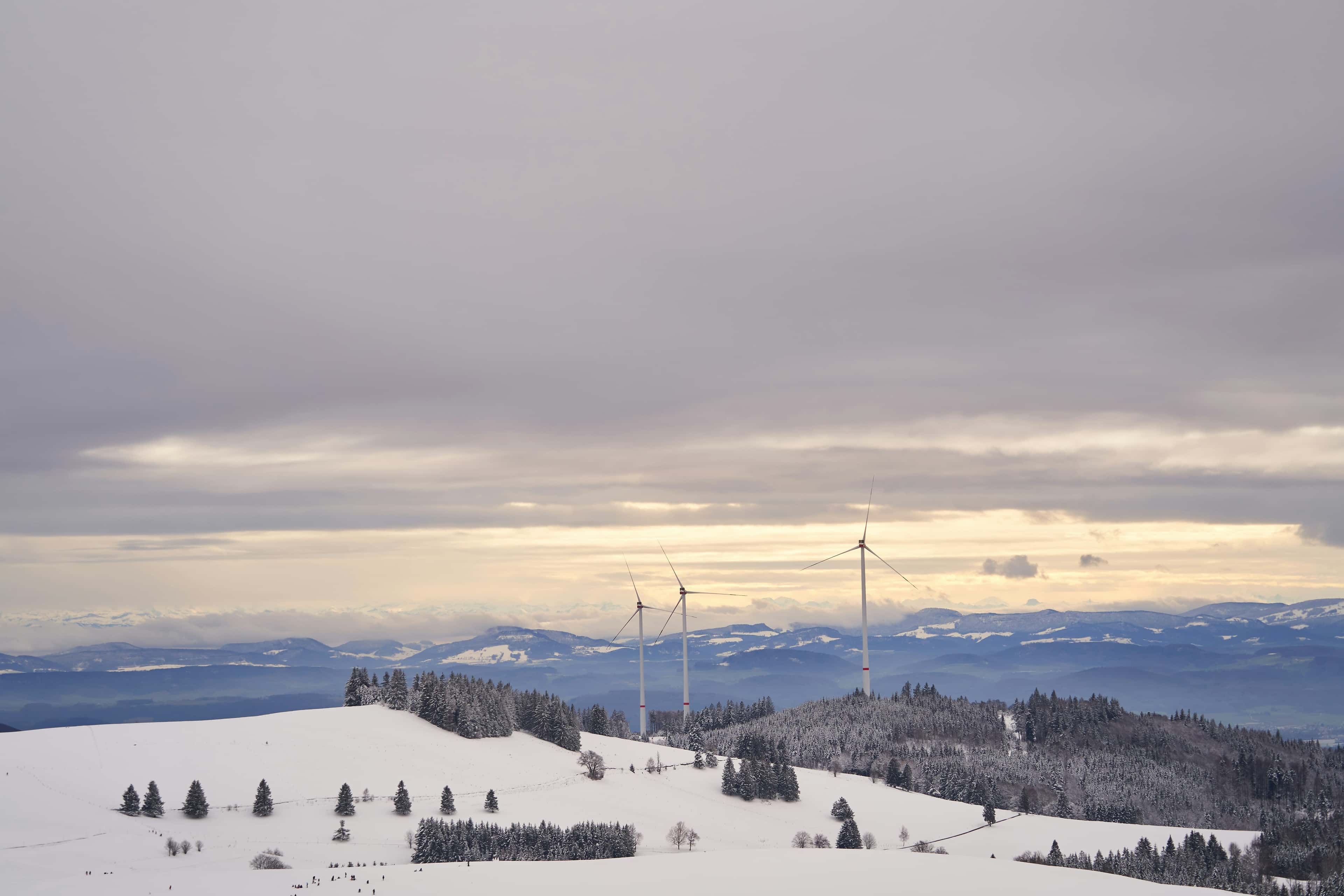 Wind turbine on snow covered ground during daytime.